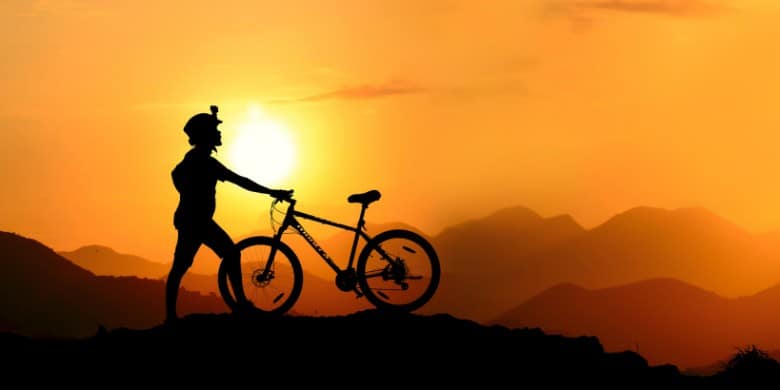 silhouette of a person on a mountain bike with the sun setting in the background