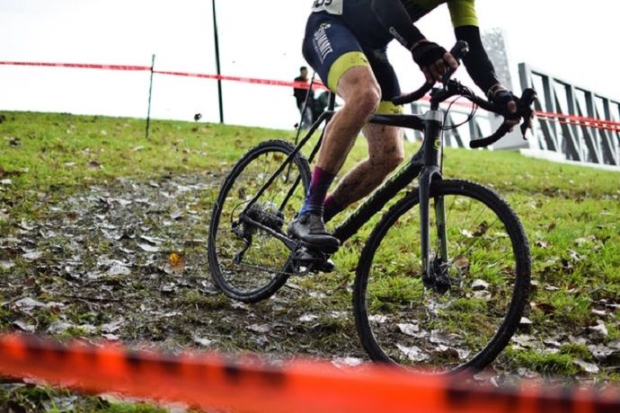 Half body shot of a man cycling through a mud and grass