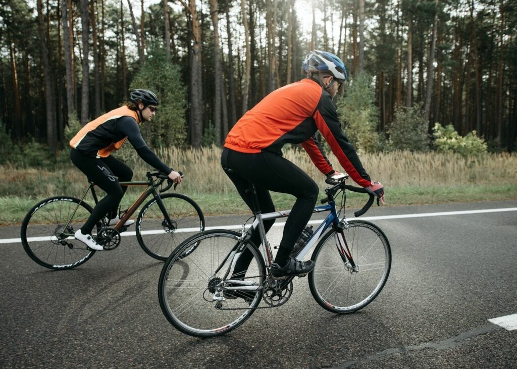 Two men with black and orange outfit cycling together