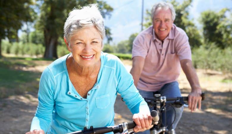 elderly couple riding bicycles on a dirt road
