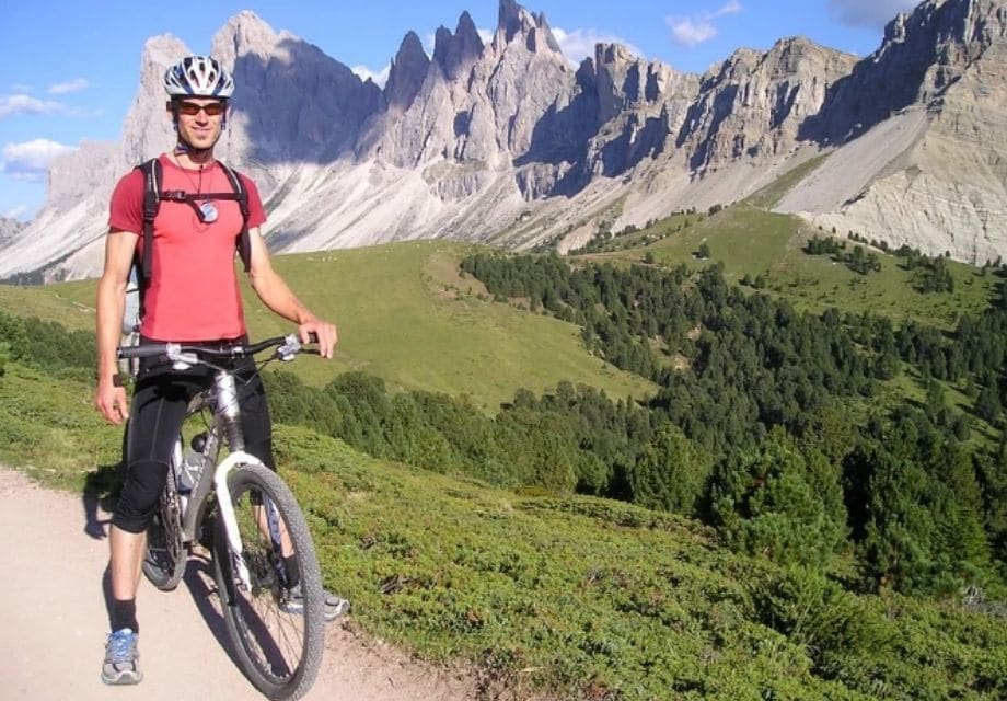 A man in red shirt on his bike and a beautiful mountain landscape background