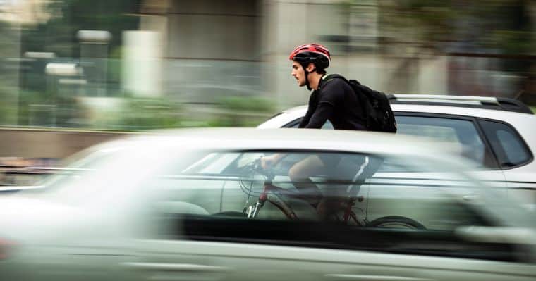 man biking near cars