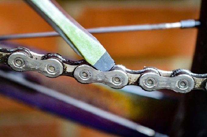 inserting screwdriver between links of bicycle's chain