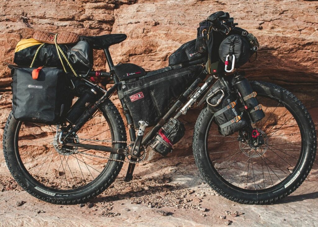 a mountain bike is parked next to some rocks loaded with bags
