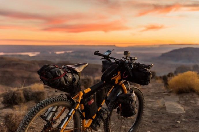 a bicycle sits on top of a mountain at sunset loaded with bags