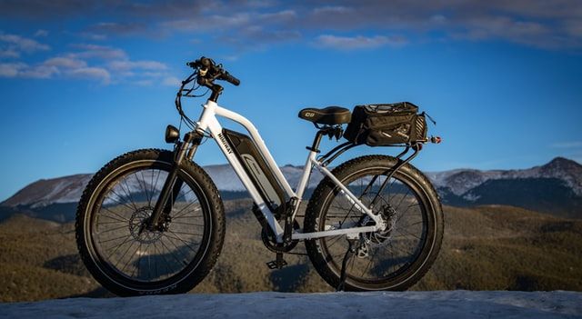 a white e-bike with a bag behind the seat on a mountainous background