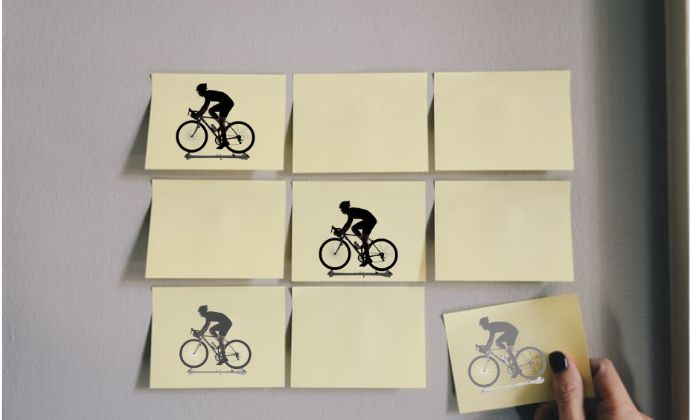 nine sticky notes with silhouette image of  a man riding a bike posted on a wall