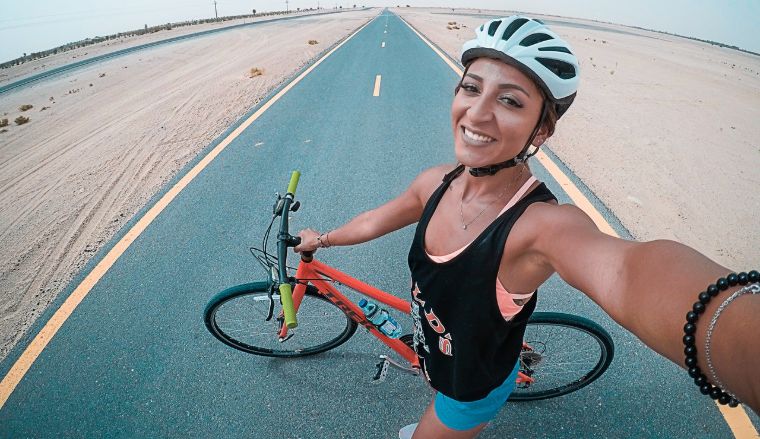 Woman making selfie with road and bike on background